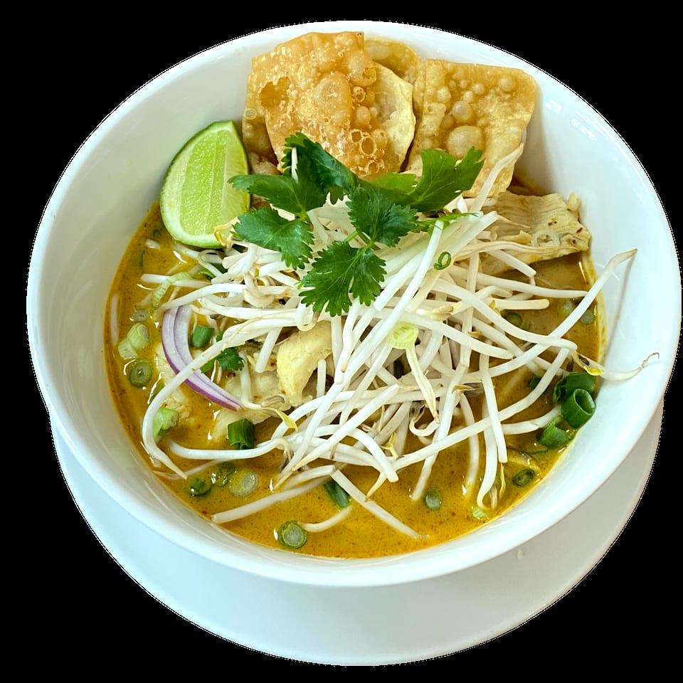 A bowl of yellow curry noodles with chicken, bean sprouts, cilantro, lime, and crispy wontons.